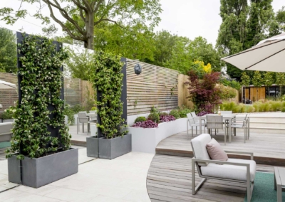Back garden design in Friern Road, Dulwich, 6 Decked seating area and patio screened by mirrors and climbing plants