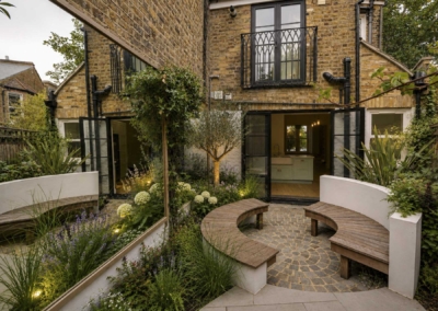 Garden design in Elmwood Rd, 1 Brick patio seating area bordered by planting, and mirrors to side