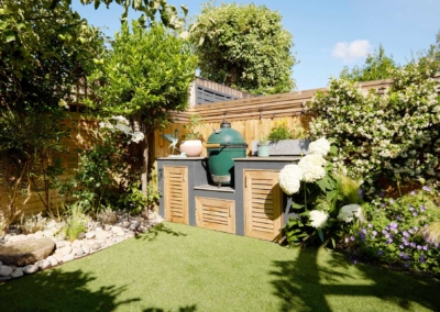 Back garden design in Frankfurt Road, 2 Lawn, borders with plants and water feature, and barbecue area.